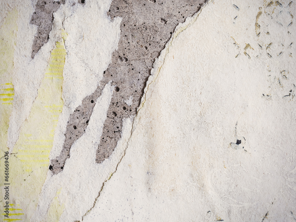 Fototapeta premium Torn old faded paper wallpaper with a retro pattern. Tattered scraps of paper on a concrete wall. Vintage texture for background and design. Closeup view with copy space.
