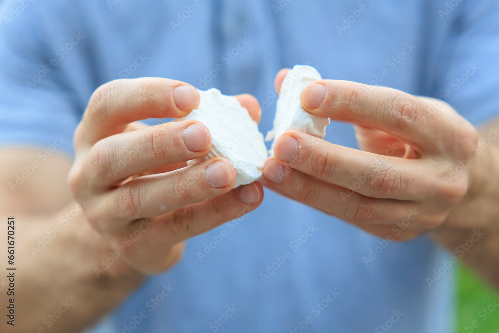 A man's hand holds a marshmallow, snack and fast food concept. Selective focus on hands with blurred background A man's hand holds a marshmallow, snack and fast food concept. Selective focus on hands with blurred background