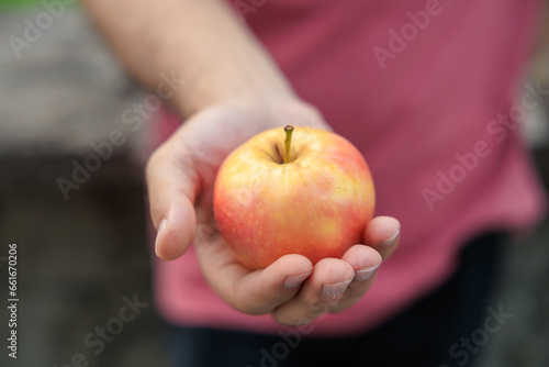 Guy's hand holds an apple, snack and fast food concept. Selective focus on hands with blurred background