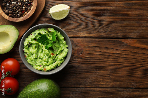 Delicious guacamole and ingredients on wooden table, flat lay. Space for text