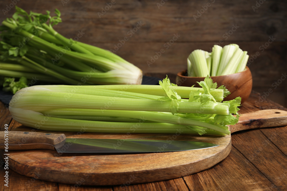 Fresh green celery bunches and knife on wooden table Fresh green celery bunches and knife on wooden table