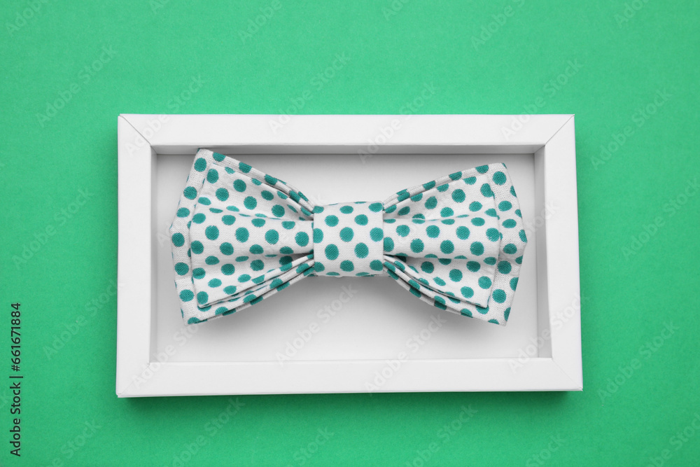 Stylish bow tie with polka dot pattern in box on green background, top view Stylish bow tie with polka dot pattern in box on green background, top view