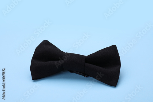Stylish black bow tie on light blue background