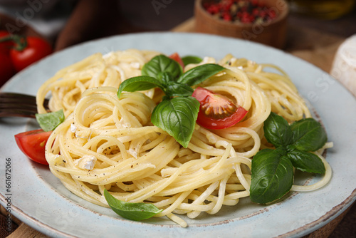 Delicious pasta with brie cheese, tomatoes and basil leaves on table, closeup