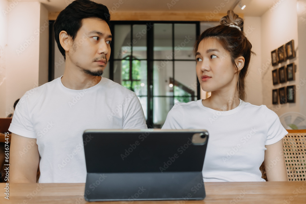 Straight faces of asian man and woman working with computer tablet in cafe. Straight faces of asian man and woman working with computer tablet in cafe.