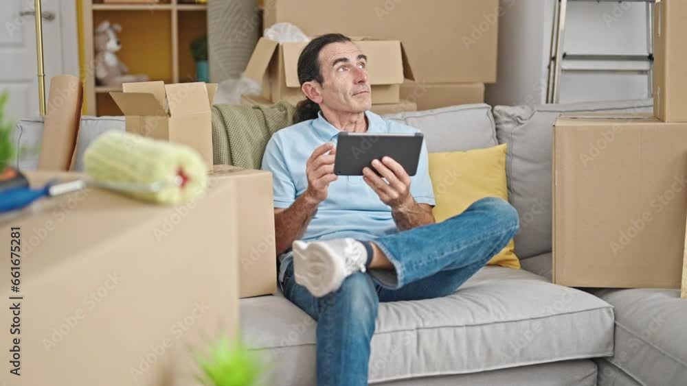 Middle age man having video call sitting on sofa at new home Middle age man having video call sitting on sofa at new home