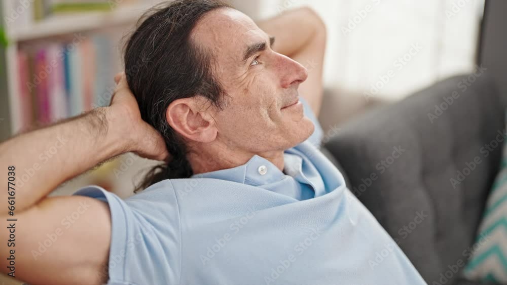 Middle age man relaxed with hands on head sitting on sofa at home Middle age man relaxed with hands on head sitting on sofa at home