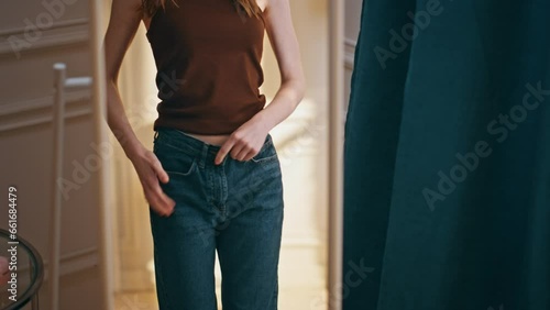 Female reflection checking weight loss progress. Smiling woman trying big jeans photo