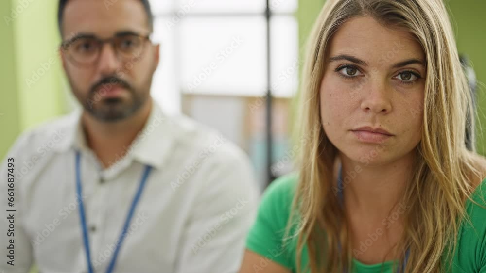 Man and woman business workers using laptop sitting on table with serious face at office Man and woman business workers using laptop sitting on table with serious face at office