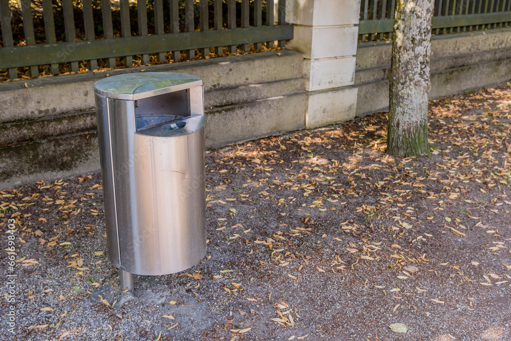 Metal trash can beside walkway in public park. Metal trash can beside walkway in public park.