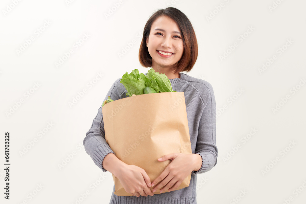 Young asian woman smiles embraces paper bag with fresh products returns from supermarket Young asian woman smiles embraces paper bag with fresh products returns from supermarket