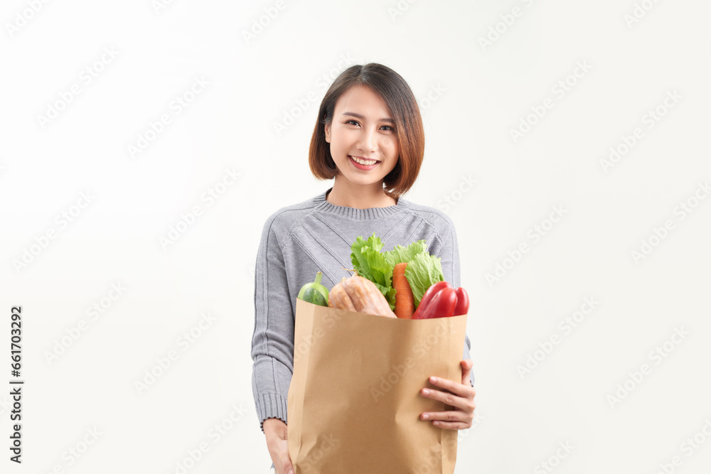 Happy woman holding paper bag full of fresh vegetable groceries isolated on white copy space background. Happy woman holding paper bag full of fresh vegetable groceries isolated on white copy space background.
