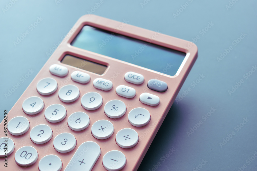 close up modern peach colour pastel calculator and white button on blue background, business and finance accounting concept close up modern peach colour pastel calculator and white button on blue background, business and finance accounting concept