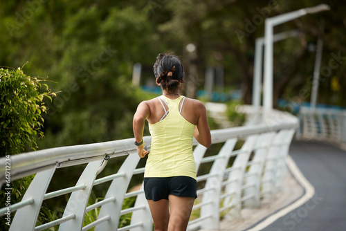 rear view young asian woman athlete running jogging outdoors in city park © imtmphoto