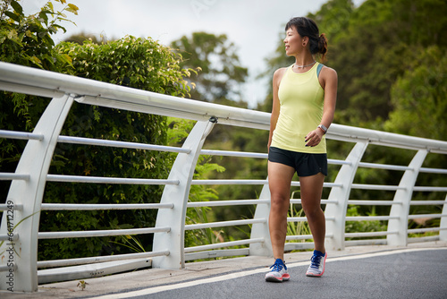 young asian woman jogger walking outdoors in park happy and smiling