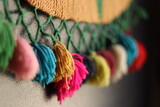 Rainbow colour Yarn Tassel Garland stitched to a piece of cloth in selective focus