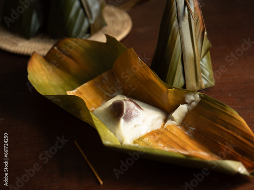 Kanom Sai Sai, Thai traditional dessert, steamed coconut cream pudding with coconut filling wrapped in banana leaf  photo