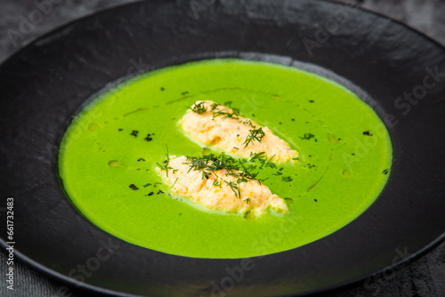 broccoli cream soup with pieces of chicken fillet on a dark background