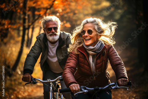 Active cheerful senior couple with bicycle, autumn public park together having fun together lifestyle. Perfect sport activities for elderly people. Happy mature couple riding bikes, bicycles in nature