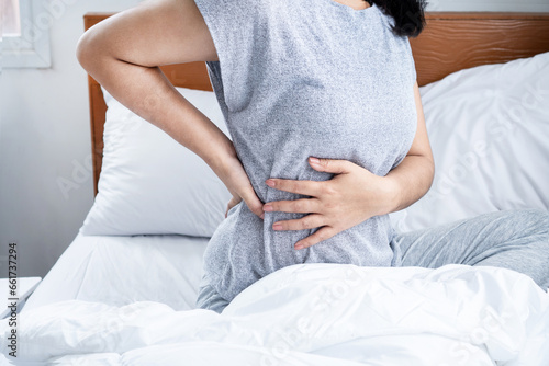 woman suffering from lower back pain , bad posture when sleeping in bed