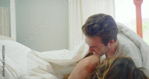 Couple in bed together, funny and tickle with love and bonding in the morning, playful in marriage and trust at home. Laughter, care free and happy, man and woman having fun in healthy relationship photo