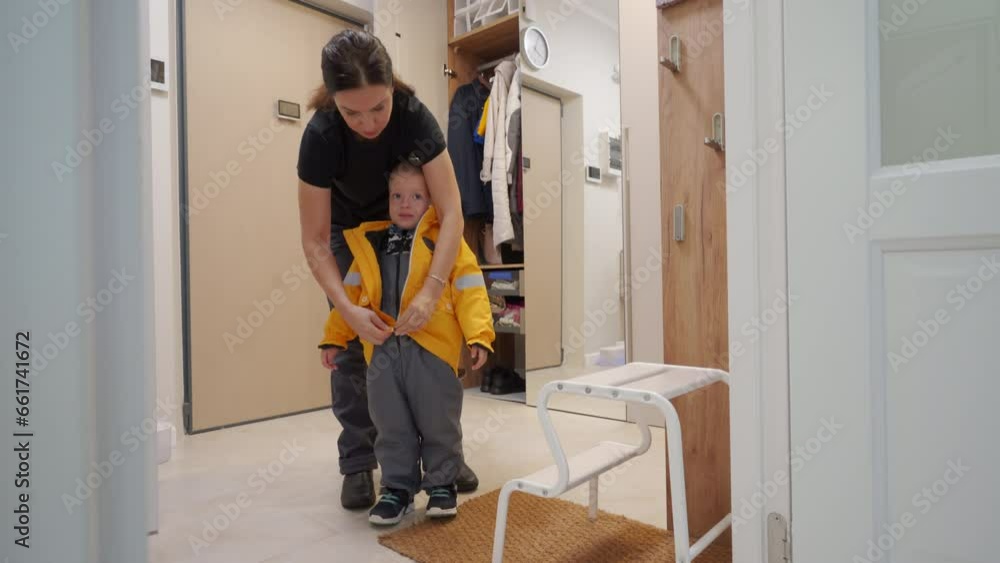 woman dresses her toddler child in warm clothes before heading out into the cold weather woman dresses her toddler child in warm clothes before heading out into the cold weather