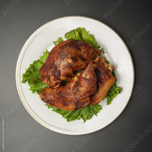 Grilled pork legs with lettuce on a white plate top view
