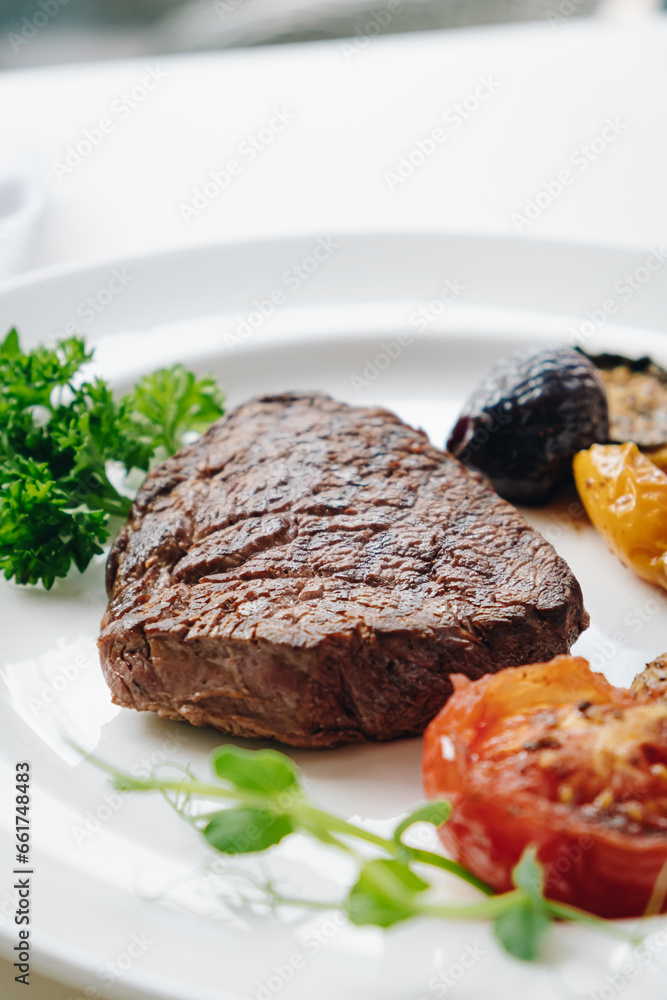 beef steak with grilled vegetables and herbs on a light background
