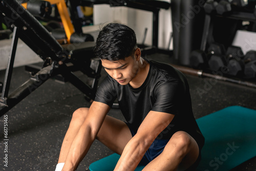 A young man doing butterfly stretch on a yoga mat. Warming up before a workout at the gym.