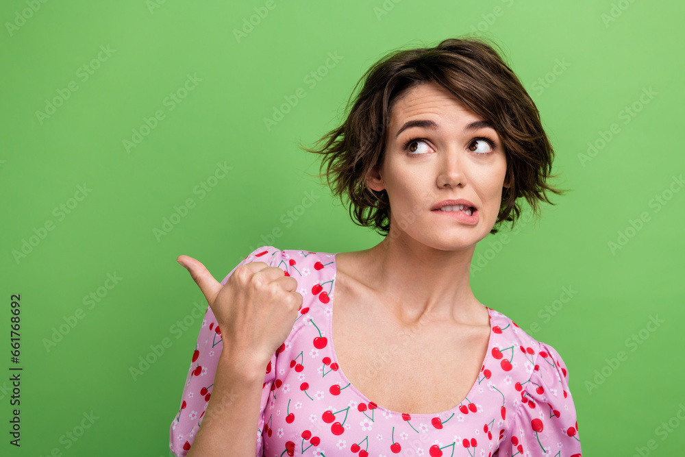 Photo of attractive young woman point frightened empty space dressed stylish pink cherry print clothes isolated on green color background Photo of attractive young woman point frightened empty space dressed stylish pink cherry print clothes isolated on green color background