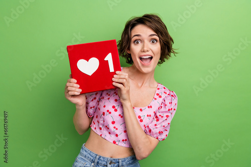 Photo of ecstatic overjoyed woman dressed pink blouse holding like icon have new follower staring isolated on green color background
