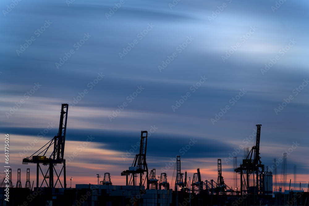 Sunset Over Busy Commercial Port with Silhouette of Massive Cranes