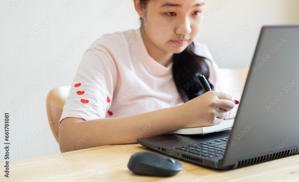 Side view of young business woman sitting at table and taking notes in notebook. Student learning online, blogger concept. Side view of young business woman sitting at table and taking notes in notebook. Student learning online, blogger concept.