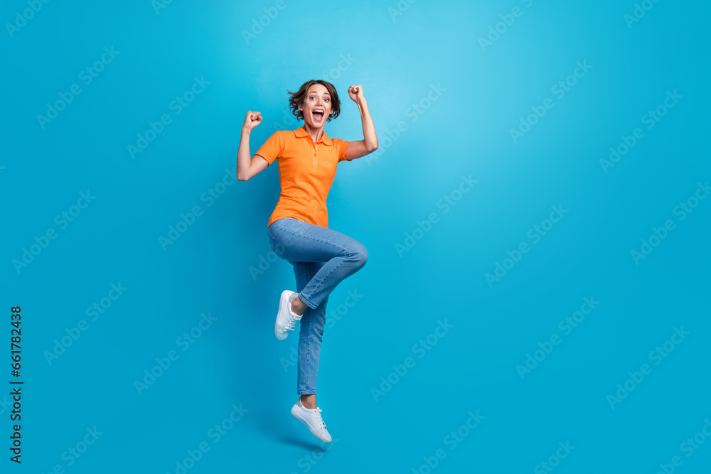 Full size photo of gorgeous girl dressed stylish polo denim trousers flying hold arms behind head isolated on blue color background