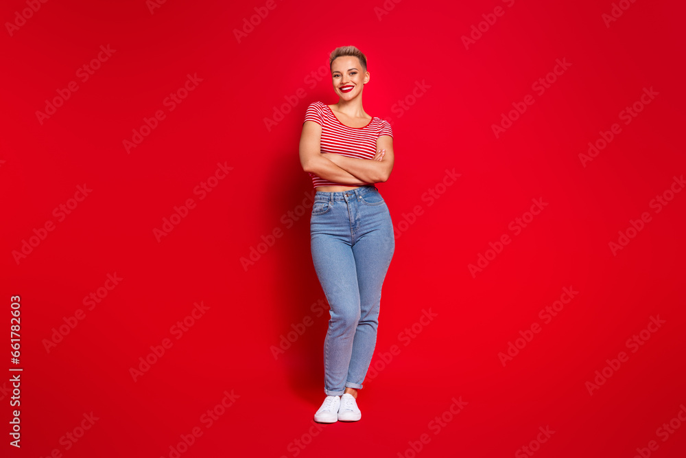 Full length photo of positive lovely girl wear stylish outfit standing with crossed hands isolated on red color background Full length photo of positive lovely girl wear stylish outfit standing with crossed hands isolated on red color background