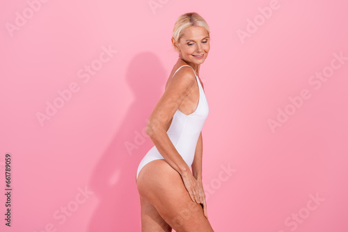 Photo of pretty lovely retired lady applying anti cellulite wrinkles cream for soft smooth skin isolated pastel color background