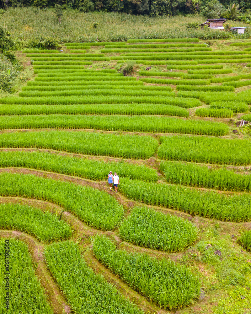 Terraced Rice Field in Chiangmai, Thailand, Pa Pong Piang rice terraces, green rice paddy fields during rain season. A couple of men and woman visit the green rice terraces during vacation