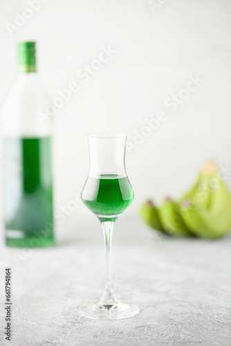 Green banana liqueur in grappas glasses and fresh bananas on the table. Copy space