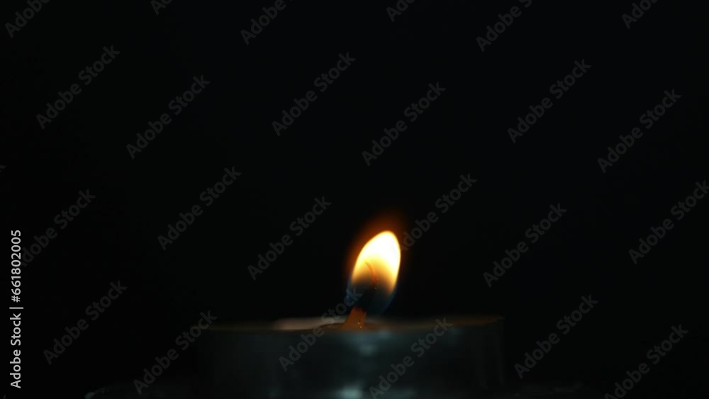 Close-up frame. A single wax candle is burning. Orange light flame. The wind blows and goes away. black darkness background night Close-up frame. A single wax candle is burning. Orange light flame. The wind blows and goes away. black darkness background night