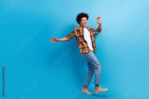 Full length photo of dreamy carefree guy wear plaid shirt dancing having fun empty space isolated blue color background