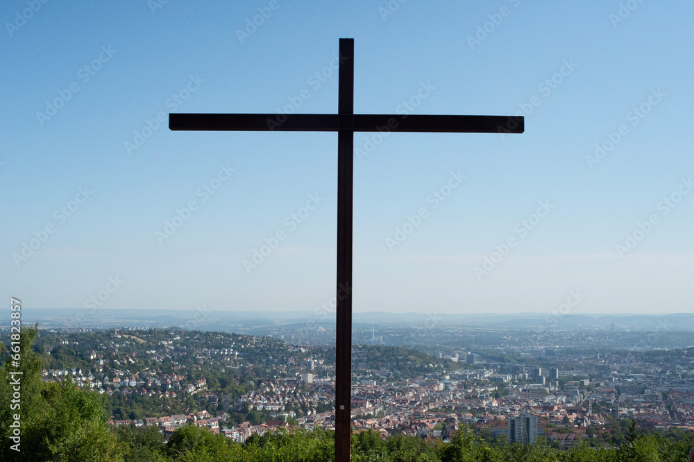 cross in the field and city view