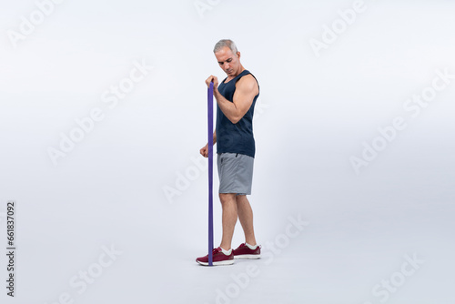 Full body length shot athletic and sporty senior man with fitness resistance band on isolated background. Healthy active physique and body care lifestyle after retirement. Clout photo