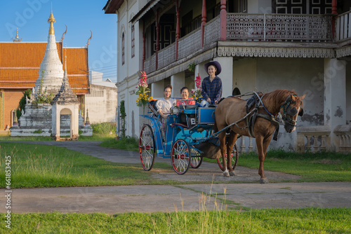 Beautiful Asian women dressed in Thai traditional dress clothing and horse-drawn carriage at Wat Chaimongkol (Jong Kaha) ancient Burmese Temple old historical evidence Burmese in Lampang, Thailand. photo