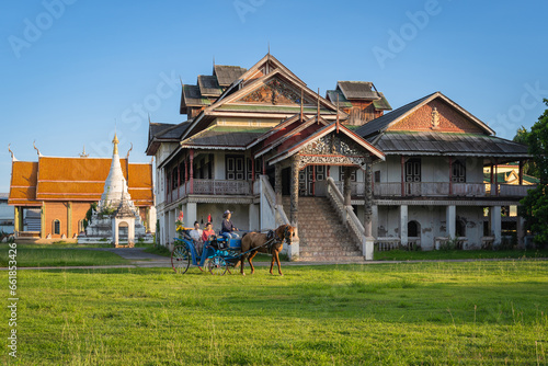 Beautiful Asian women dressed in Thai traditional dress clothing and horse-drawn carriage at Wat Chaimongkol (Jong Kaha) ancient Burmese Temple old historical evidence Burmese in Lampang, Thailand. photo