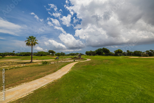 View of green grass golf field on background  blue sky with white clouds on Aruba island.  photo