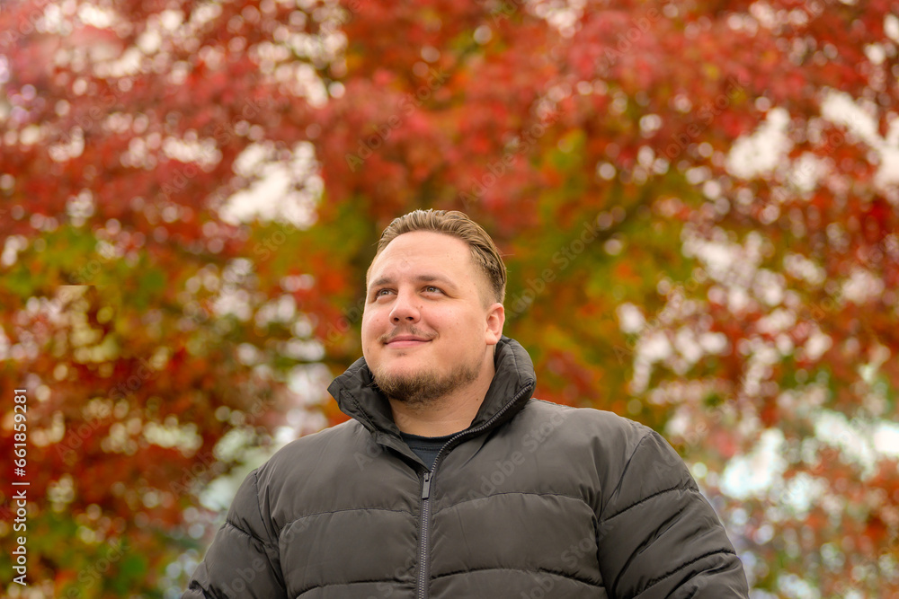 Close up of a young man in a thick winter jacket looking happily to the side Close up of a young man in a thick winter jacket looking happily to the side