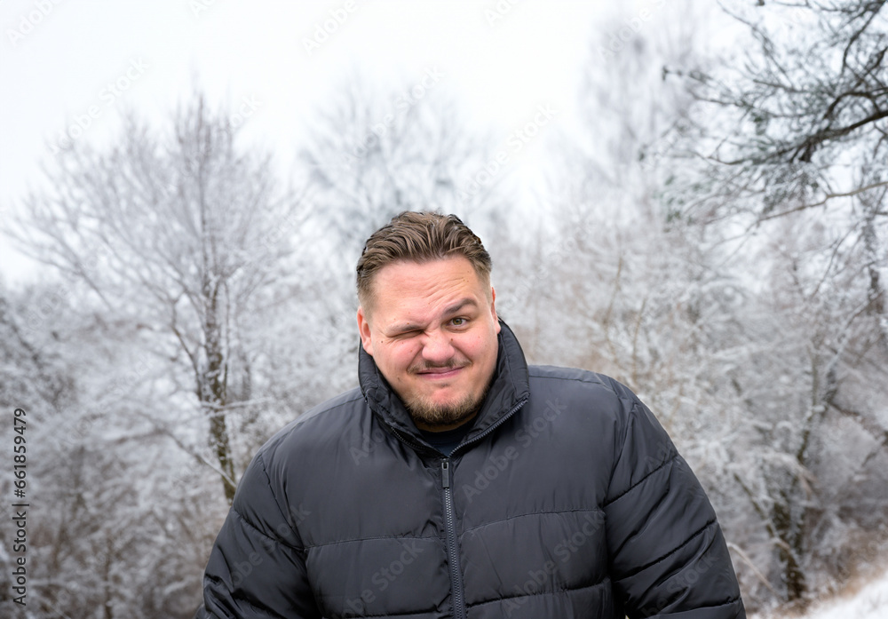 Man in a thick winter jacket looking mischievously into the camera