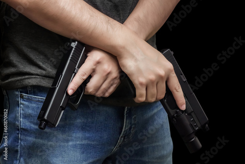 Hided handgun under the denim belt. a man in jeans and a t-shirt holds a gun in his hand from the back