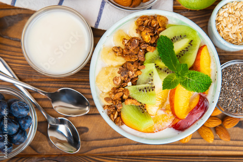 Bowl of granola with yogurt and fresh berries on a texture table. Yogurt berries  acai bowl  spirulina bowl. Healthy food  balanced breakfast. Strawberries  blueberries  kiwi  peach  almonds and chia.