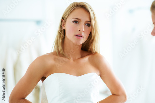 Choice, wedding dress or woman helping a bride in boutique store dressing room shopping for size. Customer, women or sales assistant with support, fabric or clothing for fitting or fashion style